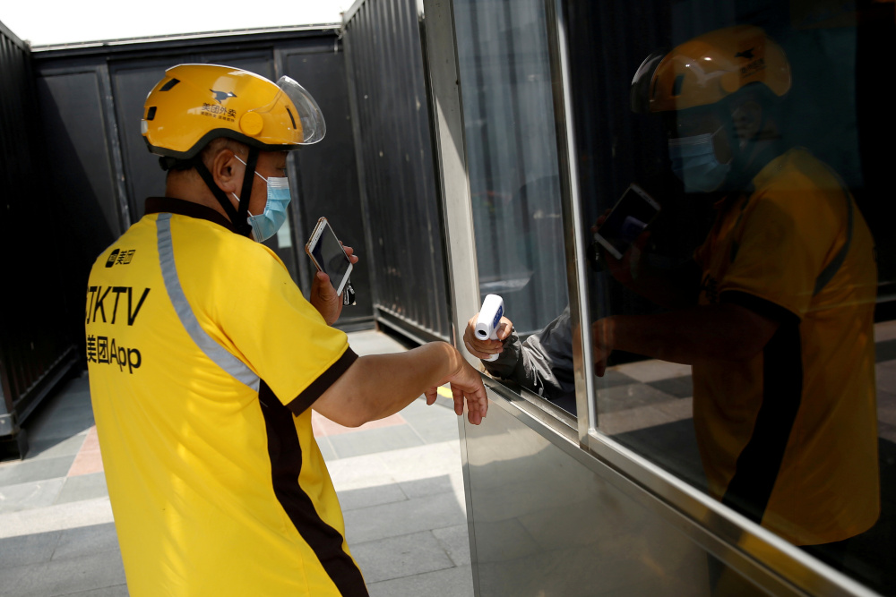 A Meituan delivery worker wearing a face mask, following the outbreak of the coronavirus disease (Covid-19), has his temperature checked as he enters a shopping complex, in Beijing July 15, 2020. u00e2u20acu201d Reuters pic