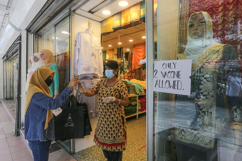 A shop worker checks a customer’s Covid-19 vaccination status in Kuala Lumpur August 17, 2021. — Picture by Yusof Mat Isa