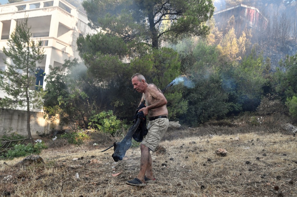 A local resident removes a smouldering tree branch to prevent fire restarting in the suburb of Thrakomakedones near Mount Parnitha, north of Athens on August 7, 2021. u00e2u20acu201d AFP pic