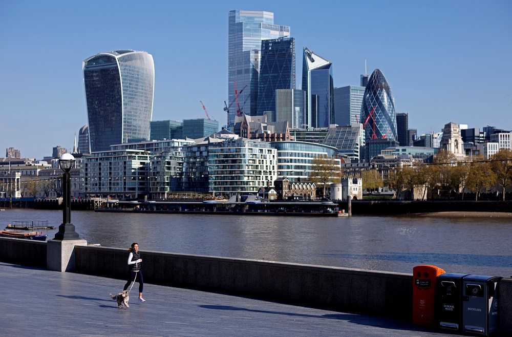 A woman exercises with a dog near the City of London financial district, in London April 30, 2021. u00e2u20acu201d Reuters pic