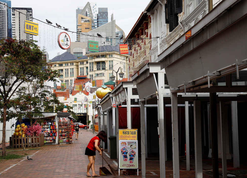 A woman sweeps the floor near closed down shops in the largely empty Chinatown tourist district, Singapore August 30, 2021. u00e2u20acu201d Reuters pic