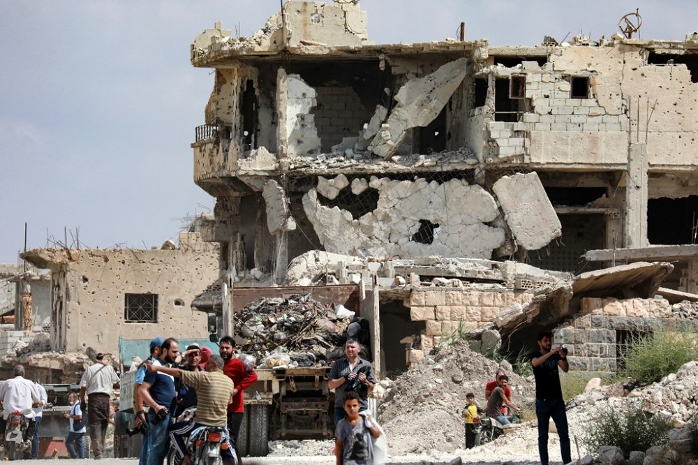 A picture taken during a tour organised by the Syrian Ministry of Information shows people gathered in front of a heavily damaged building in the district of Daraa al-Balad of Syriau00e2u20acu2122s southern city of Daraa September 12, 2021. u00e2u20acu201d AFP pic