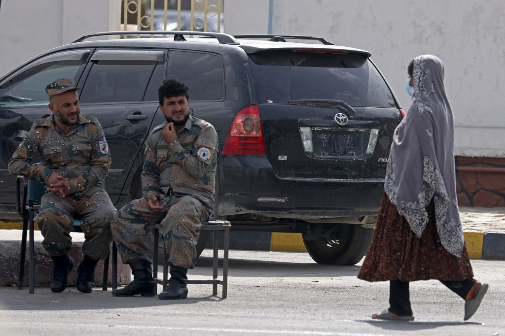 A woman walks past Afghan Border National Police personnel outside the airport in Kabul on September 12, 2021. — AFP pic