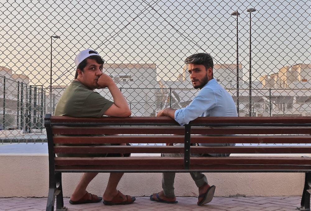 Afghan refugees Khalid Andish (right), 24, and Ahmad Wali Sarhadi, 28, sit on a bench near their accommodation at Park View Villas, a Qatar’s 2022 FIFA World Cup residence in Doha, on September 2, 2021. — AFP pic