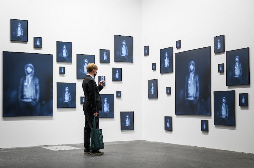 A visitor takes a photo with his mobile phone of u00e2u20acu02dcRepeating the Obvious, 2019u00e2u20acu2122, an artwork by US artist Carrie Mae Weems, exhibited in the Unlimited sector of Art Basel, the worldu00e2u20acu2122s premier modern and contemporary art fair, in Basel, on September 21