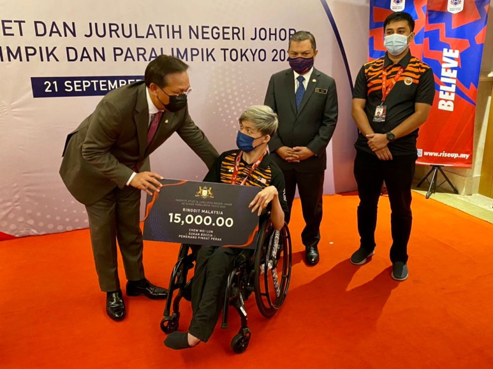 Johor Mentri Besar Datuk Hasni Mohammad (left) presents a mock cheque to Tokyo 2020 Paralympic Games silver medallist Chew Wei Lun September 21, 2021. u00e2u20acu201d Picture by Ben Tan