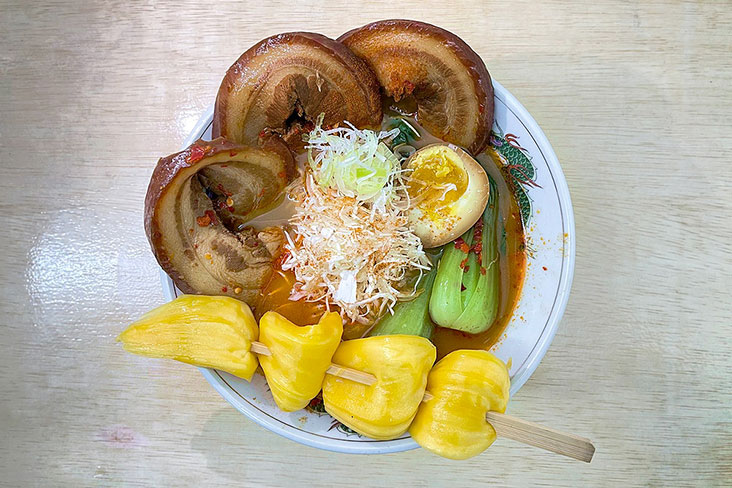 Spicy pork broth and a skewer of jackfruit complement each other in a bowl of Volcano Ramen.