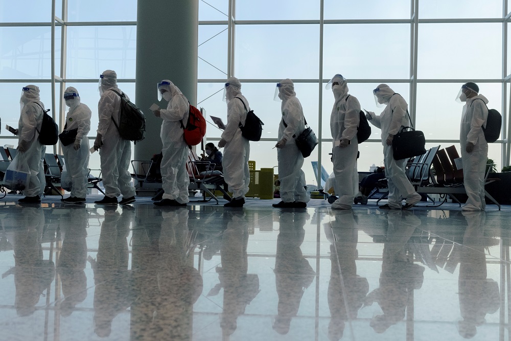 Passengers wearing protective suits (PPE) line up to board their plane for an international flight at Hong Kong airport, July 9, 2021. u00e2u20acu2022 Reuters file pic