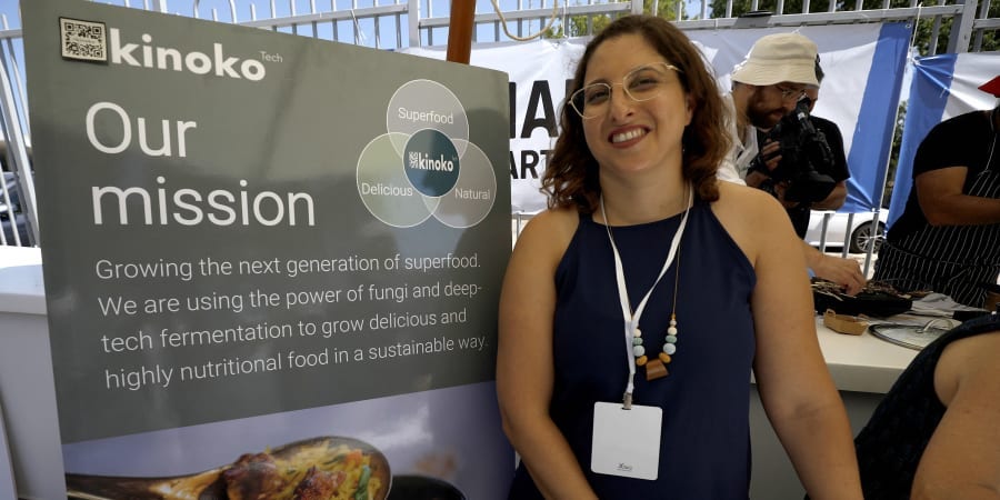 Kinoko-Tech co-founder and chief executive Jasmin Ravid poses for a photo next to her company banner during the Margalit Startup City Galil street foodtech event in the northern Israeli town of Kiryat Shmona. u00e2u20acu201d ETX Studio pic