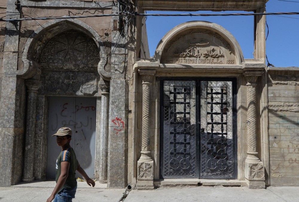A young boy walks in front of the entrance gate of the Syriac Christian church of Mar Tuma in Iraq's second city of Mosul, in the northern Nineveh province, under restoration on September 14, 2021. — AFP pic