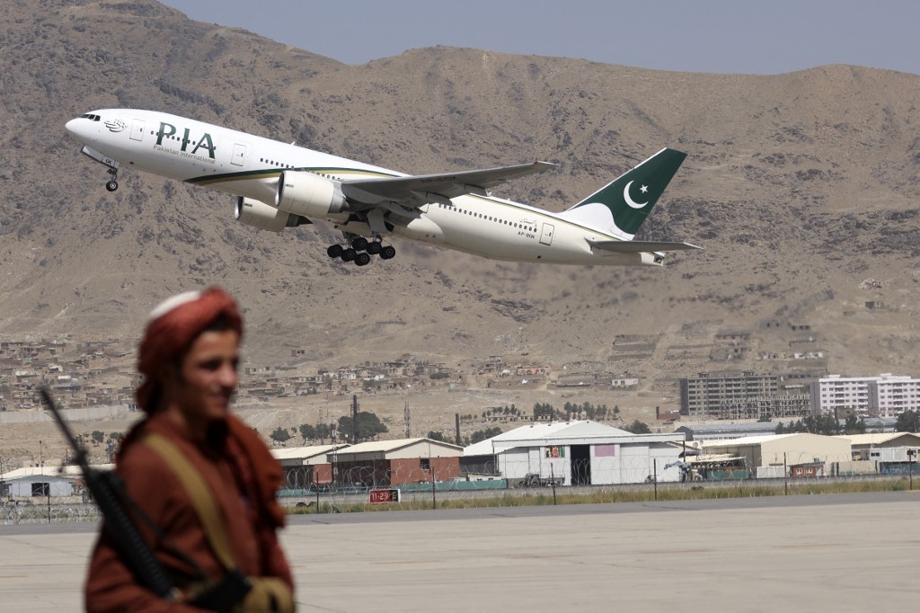 A Taliban fighter stands guard as a Pakistan International Airlines plane, the first commercial international flight to land since the Taliban retook power last month, takes off with passengers onboard at Kabul airport , September 13, 2021. u00e2u20acu201d AFP pic