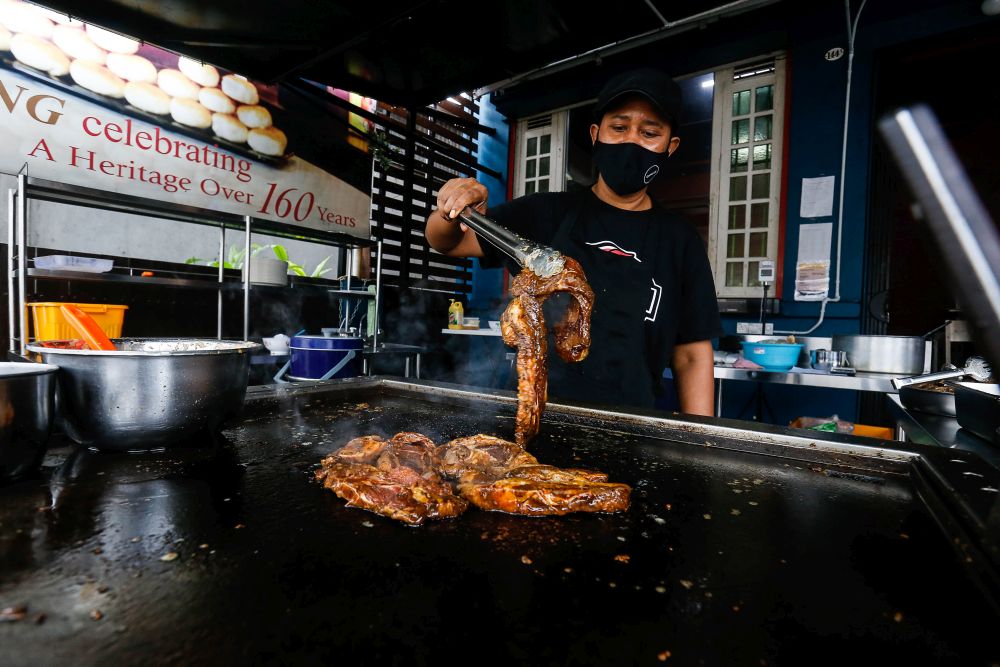 Yatt Abdul Hamid works the hot plate at Quallys Nusantara Kitchen on Jalan Burmah, George Town on September 21, 2021. 