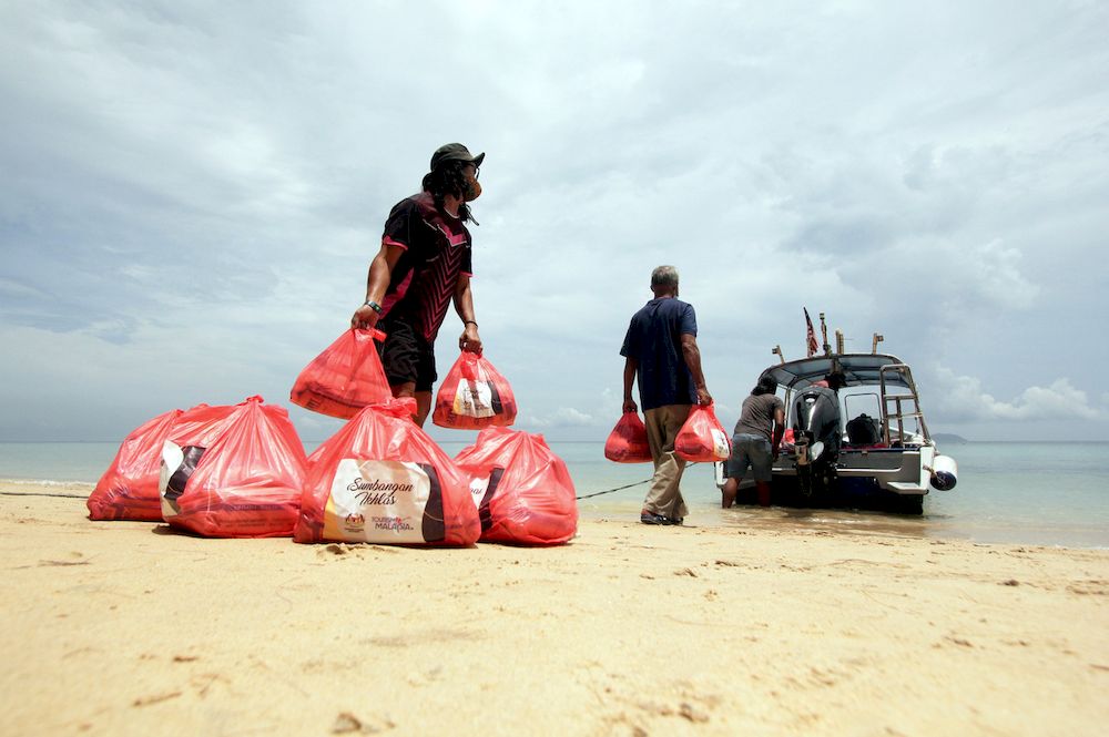 Representatives of food aid recipients loading food baskets into a boat after the donation handover ceremony, in Kampung Tekek, Pulau Tioman, September 6, 2021. u00e2u20acu201d Bernama pic