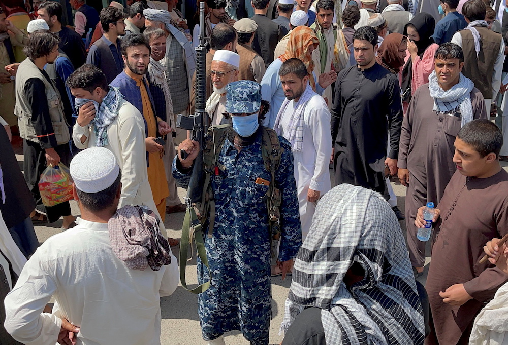 A member of Taliban security forces stands guard among crowds of people walking past in a street in Kabul, Afghanistan September 4, 2021. — Reuters pic