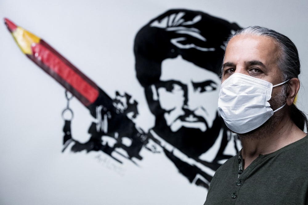 Aghan artist and co-founder of the ArtLords collective, Farshad poses in front of a symbolic drawing of his collective, a Taliban fighter whose rocket launcher is filled with pencils in Paris on September 11, 2021.  u00e2u20acu201d AFP pic