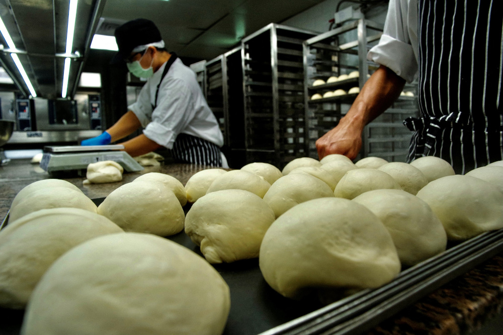 Employees from Taiwan company JustKitchen, a network of u00e2u20acu02dcghost kitchensu00e2u20acu2122 that make delivery-only food, preparing to bake bread for takeaway meals at one of their locations in Taipei. u00e2u20acu201d AFP pic