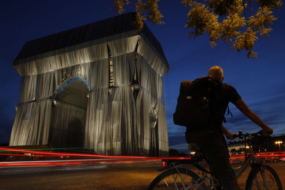 nA cyclist looks at the Arc de Triomphe, in Paris, wrapped in silver-blue fabric as it was designed by the late artist Christo, in the evening of September 13, 2021. u00e2u20acu201d Reuters picn