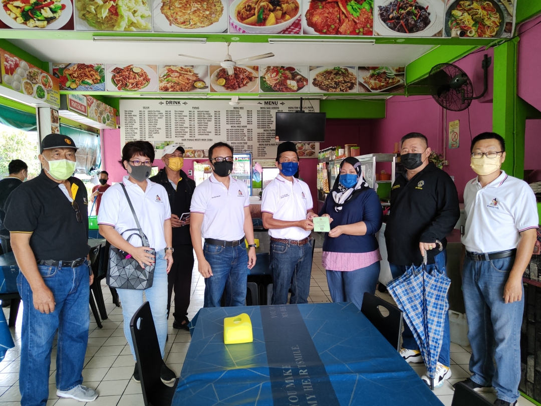 Bujang (fourth right) hands over a vaccination certificate to owner of Noor Satay Islamic Cafe and Seafood, Nuraini Ahmad, while Ting (second left), Izkandar (fourth left), Lim (second right) and others look on. u00e2u20acu2022 Borneo Post pic