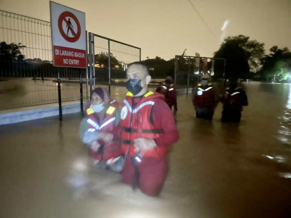 A fireman evacuating Kamariah Kanto after she and her husband were trapped in their house due to flash floods, September 2, 2021. u00e2u20acu201d Picture courtesy of the Johor Fire and Rescue Department
