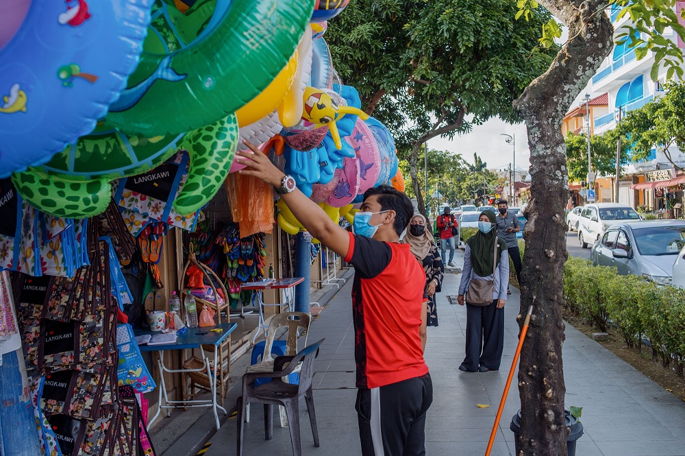 A vendor is seen serving a customer at one of the shops along Pantai Cenang in Langkawi.