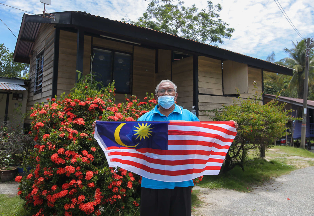 Tok Batin Anjang Alang poses with the Jalur Gemilang at Kampung Orang Asli Chadak, Ulu Kinta in Perak September 15, 2021. — Picture by Farhan Najib