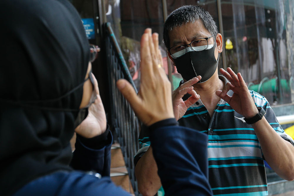 Abdul Azim Khor Tien Sun, 50, speaks with Malay Mail using sign language as his wife Siti Zubaidah Mohd Lani, 39 translates during an interview in Jalan Burma, Penang September 15, 2021. — Picture by Sayuti Zainudin