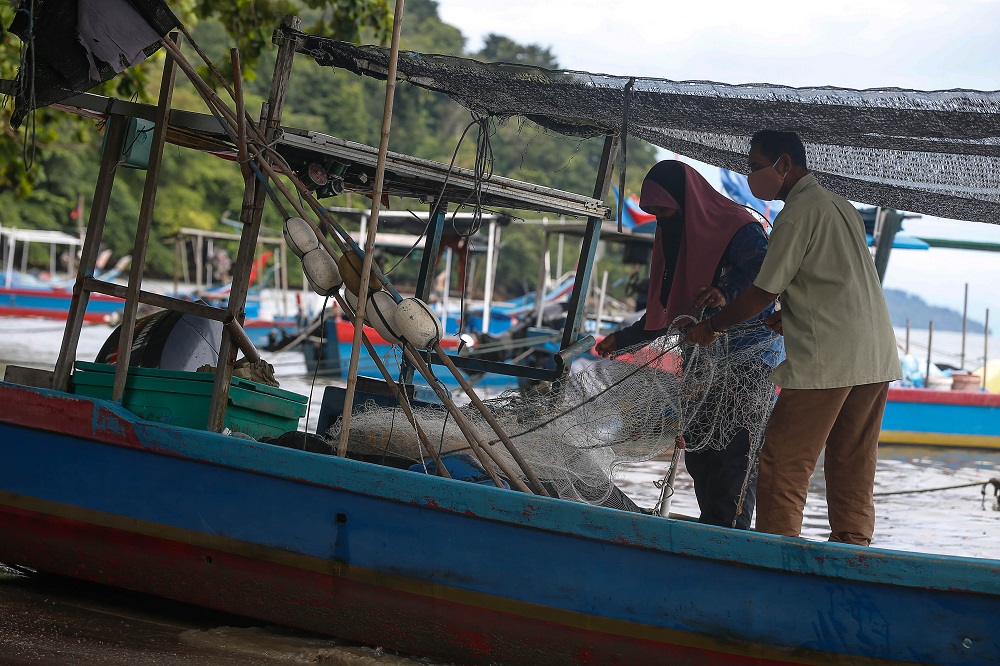Fajinah Jaafar (left), 60, and Haris Abdullah (right), 61, checking the fishing net on a boat at Gertak Sanggul in Penang September 13, 2021. 