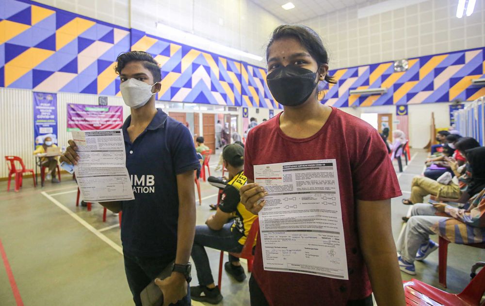 Siblings Rickneshwaran Govindasamy (left) and Tushalini Govindasamy show their vaccination cards after receiving their Covid-19 jab at the Kinta Town Hall in Batu Gajah September 21, 2021. — Picture by Farhan Najib