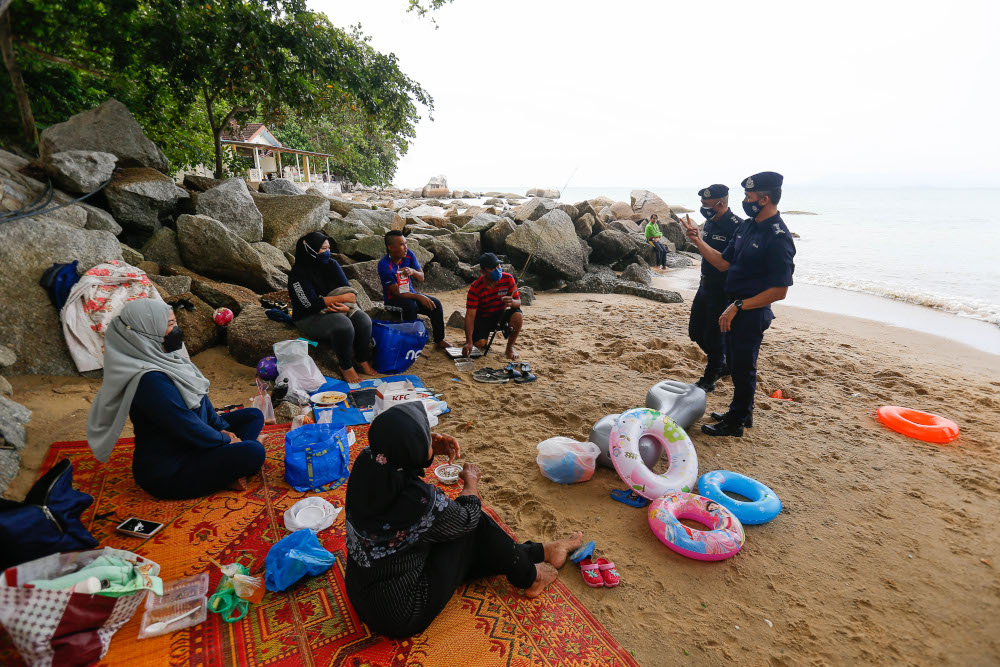 Penang CPO Datuk Mohd Suhaily Mohd Zain (left) along with North-east District Police Chief ACP Soffian Santong speak to beachgoers during the public holiday at Shamrock Beach, Batu Ferringhi, September 16, 2021. u00e2u20acu201d Picture by Sayuti Zainudin