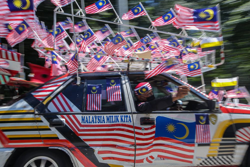 Tazar Alang Ibrahim takes to the streets in his Saga adorned with the Jalur Gemilang August 23, 2021. u00e2u20acu201d Picture by Farhan Najib
