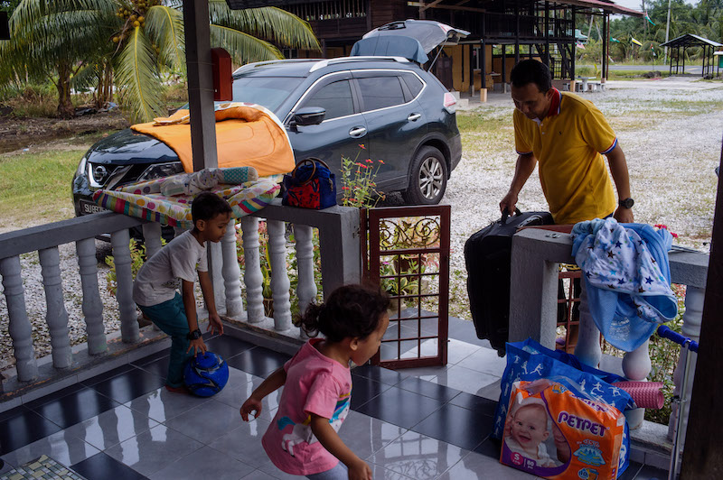Taufik unloads his luggage upon arrival at his parents' home in Bagan Datuk. — Picture by Shafwan Zaidon
