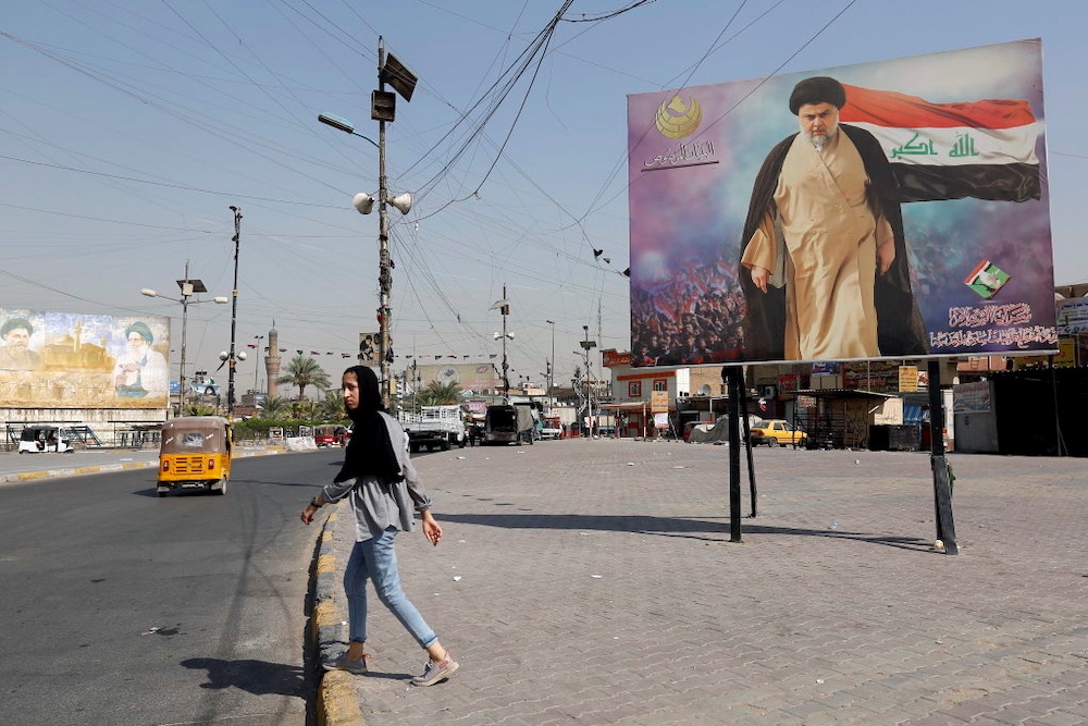 A girl walks near a poster depicting Iraqi Shiah Muslim cleric Moqtada al-Sadr, whose party was the biggest winner in initial election results, in the Sadr City district of Baghdad, Iraq October, 12, 2021. u00e2u20acu201d Reuters pic