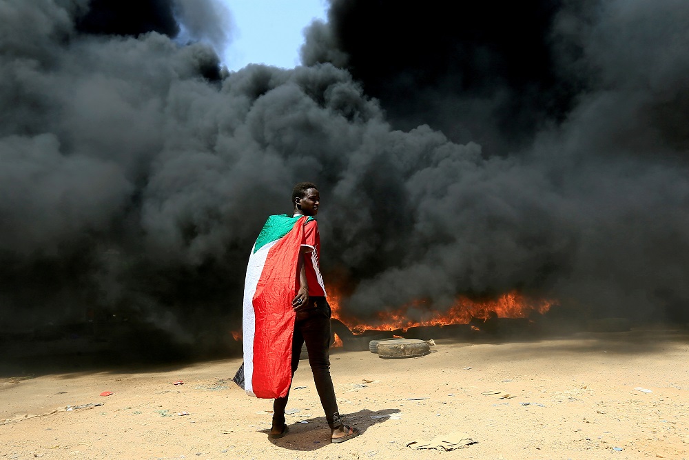A person wearing a Sudan's flag stand in front of a burning pile of tyres during a protest against prospect of military rule in Khartoum, Sudan October 21, 2021. u00e2u20acu201d Reuters pic