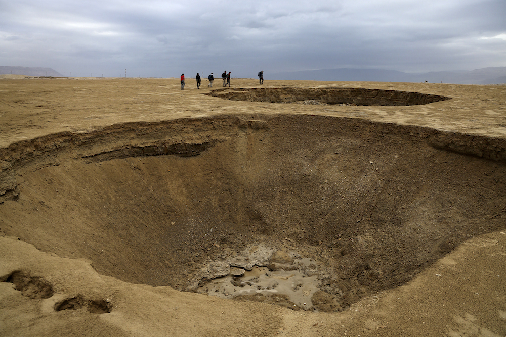Hikers walk next to sinkholes across a dried-up sea area which exposed and created a salt plain, some 20km south of the Israeli Kibbutz Ein Gedi January 15, 2021. u00e2u20acu201d AFP pic