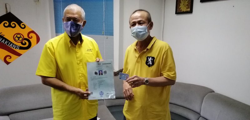 Wong (right) happily shows his MyKad to Ting. u00e2u20acu201d Borneo Post pic