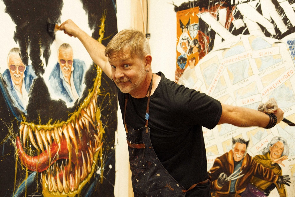Artist Rob Prior poses in front of two large paintings featuring Stan Lee and X Men portraits, in Los Angeles, California September 21, 2021 in this handout image. u00e2u20acu2022 Rob Prior u00e2u20acu2022 Mogul Productions/Handout via Reuters