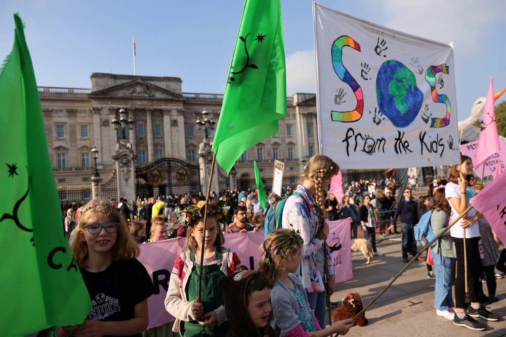School students and parents carry placards as they gather in order to hand over a 100,000-signature petition urging the Royal Family to rewild their land, outside Buckingham Palace in central London on October 9, 2021, ahead of the Cop26 climate talks. u00e2u20ac