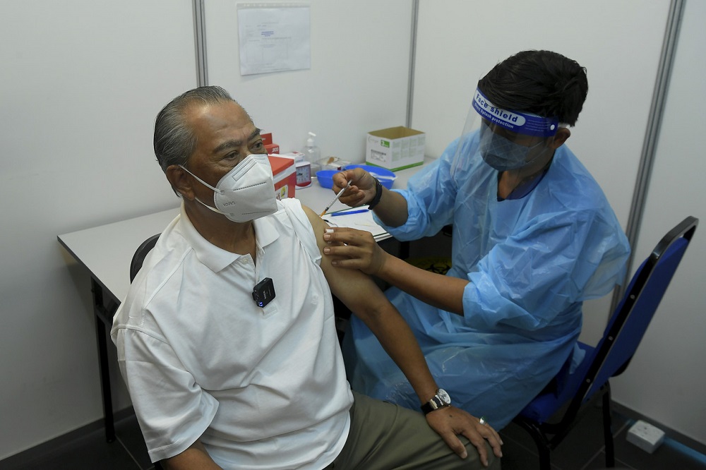 Tan Sri Muhyiddin Yassin (left) receives his Covid-19 booster shot at the vaccination centre at the Bukit Jalil Axiata Arena in Kuala Lumpur October 23, 2021. u00e2u20acu201d Bernama pic