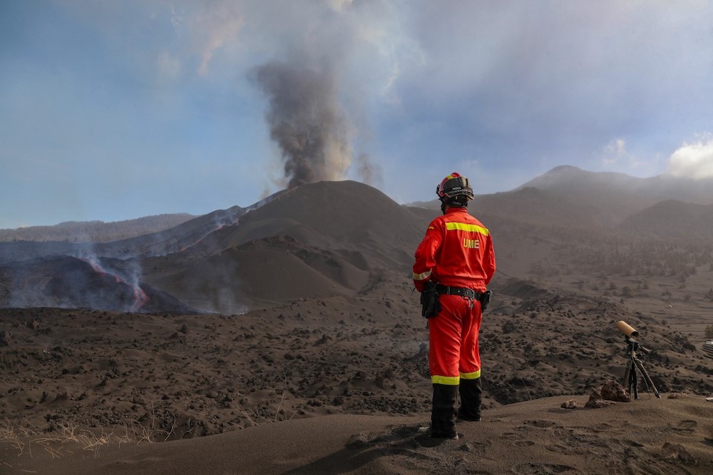 In this handout photograph taken and released by the Spanish Military Emergency Unit on October 29, 2021, a UME member monitors the evolution of the lava flow, during the eruption of the Cumbre Vieja volcano, on the Canary island of La Palma. u00e2u20acu2022 AFP pic