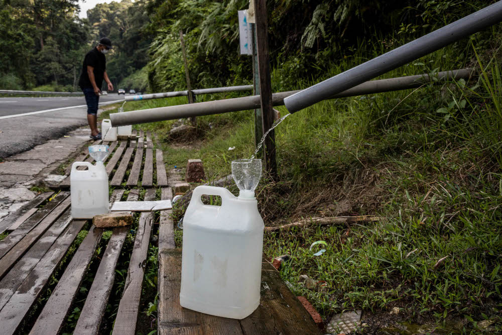 A man refills water containers from hill water during water supply disruption in Jalan Ulu Yam, October 13, 2021. u00e2u20acu201d Picture by Firdaus Latif