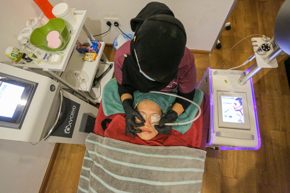 A Hannan Medispa Ipoh beautician performs a facial treatment on a client in conjunction with the shop’s opening, October 1, 2021. — Picture by Farhan Najib 