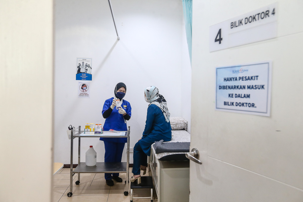 Ajwa Clinic Medical assistance Halisah Munawar explains to Norhasliza Abdullah how to use a self Covid-19 test kit before she heads to her hometown in Kelantan, in Shah Alam, October 12, 2021. u00e2u20acu201d Picture by Yusof Mat Isa 