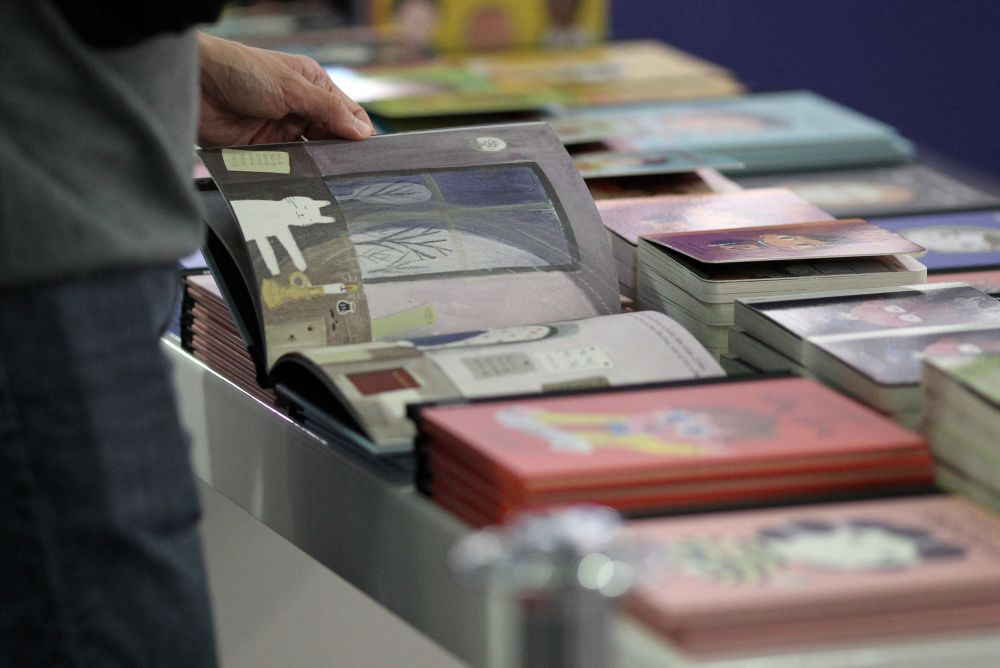 A visitor flips through a book at a booth at the Frankfurt Book Fair 2021 in Frankfurt on October 20, 2021. u00e2u20acu201d Reuters pic