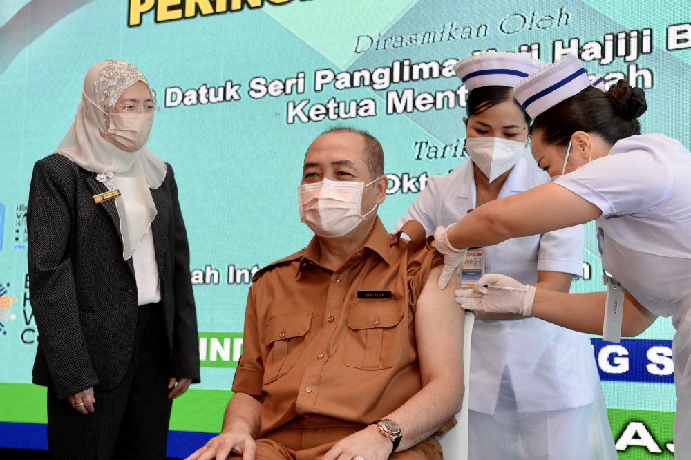 Sabah Chief Minister Datuk Seri Hajiji Noor receives his Covid-19 booster shot as state health director Datuk Rose Nani Mudin looks on in Kota Kinabalu October 20, 2021. u00e2u20acu201d Picture by Julia Chan