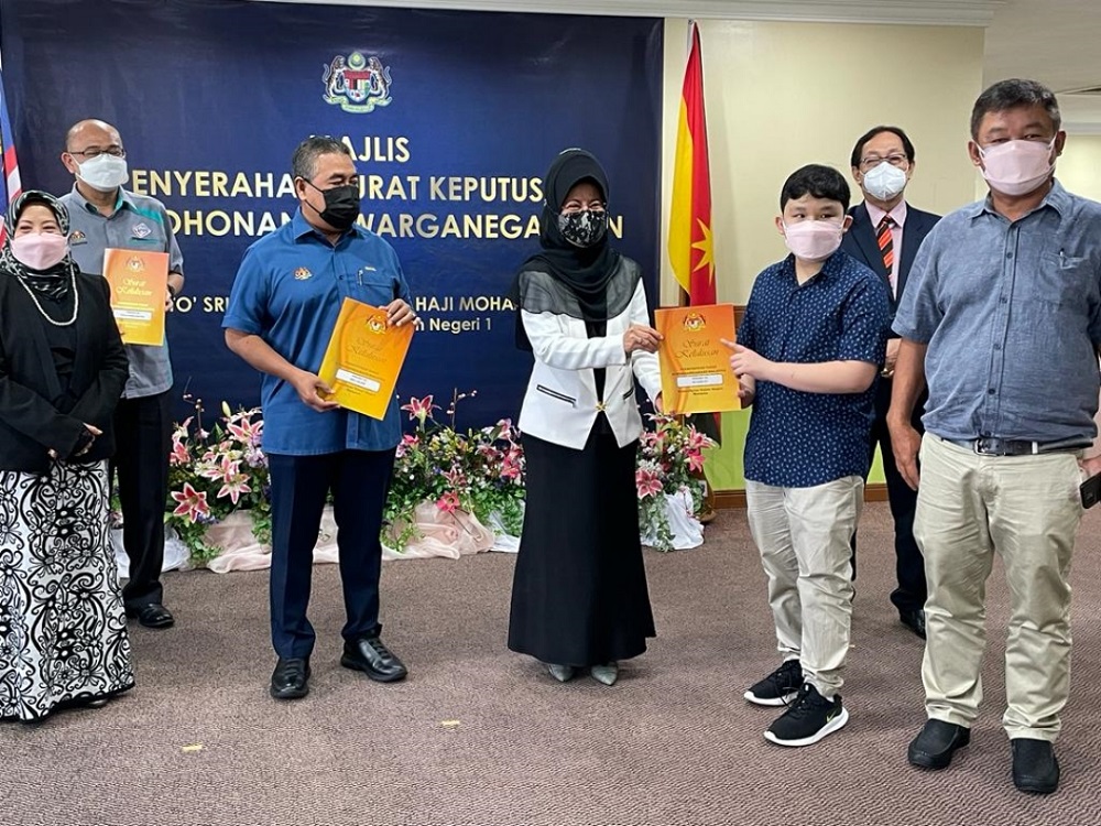 Fatimah (centre) hands over approval letter to an applicant at the ceremony, as Ismail (on her right), Rosey (left), Harden (back, right) and others look on. u00e2u20acu201d Borneo Post Online pic