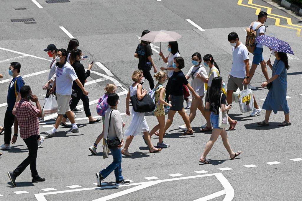 People walk at a pedestrian crossing along the Orchard Road shopping district in Singapore. u00e2u20acu2022 AFP pic