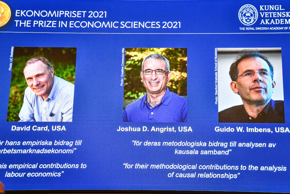 Photographs of the 2021 Nobel economics prize winners David Card, Joshua Angrist and Guido Imbens appear on a screen during the announcement of the award in Stockholm October 11, 2021. u00e2u20acu201d Claudio Bresciani/TT News Agency pic via Reuters 