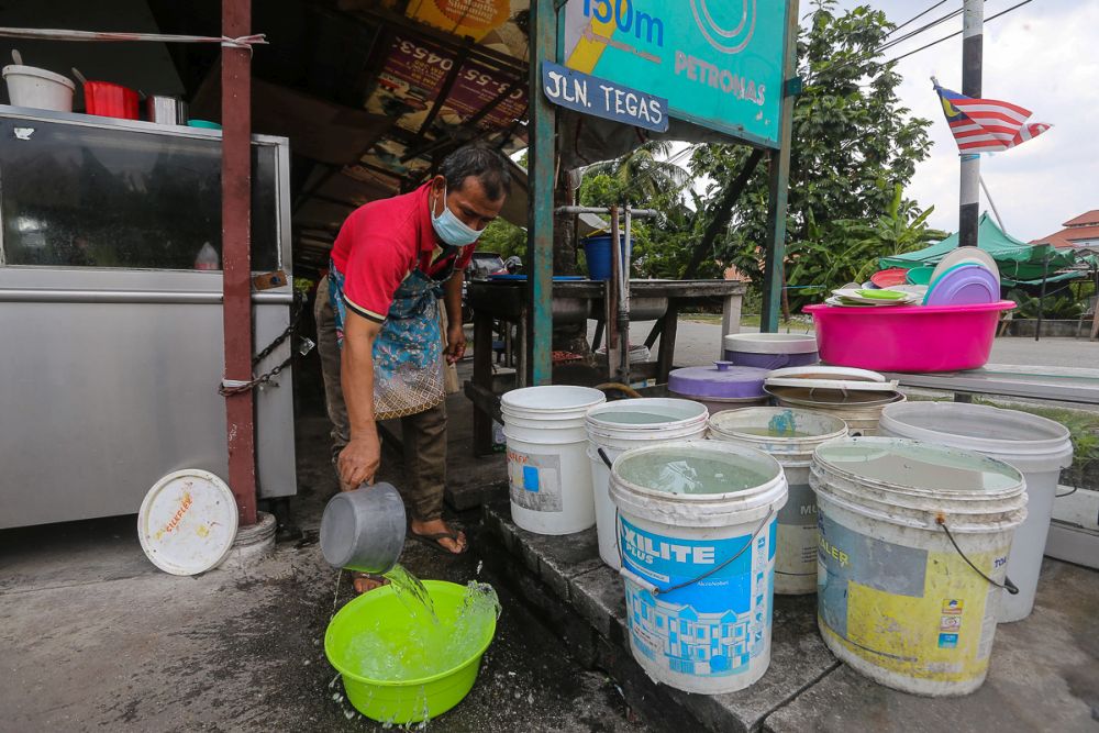A worker fills a plastic container with water amid water supply disruption in Kampung Jawa, Klang October 13, 2021. u00e2u20acu201d Picture by Yusof Mat Isa