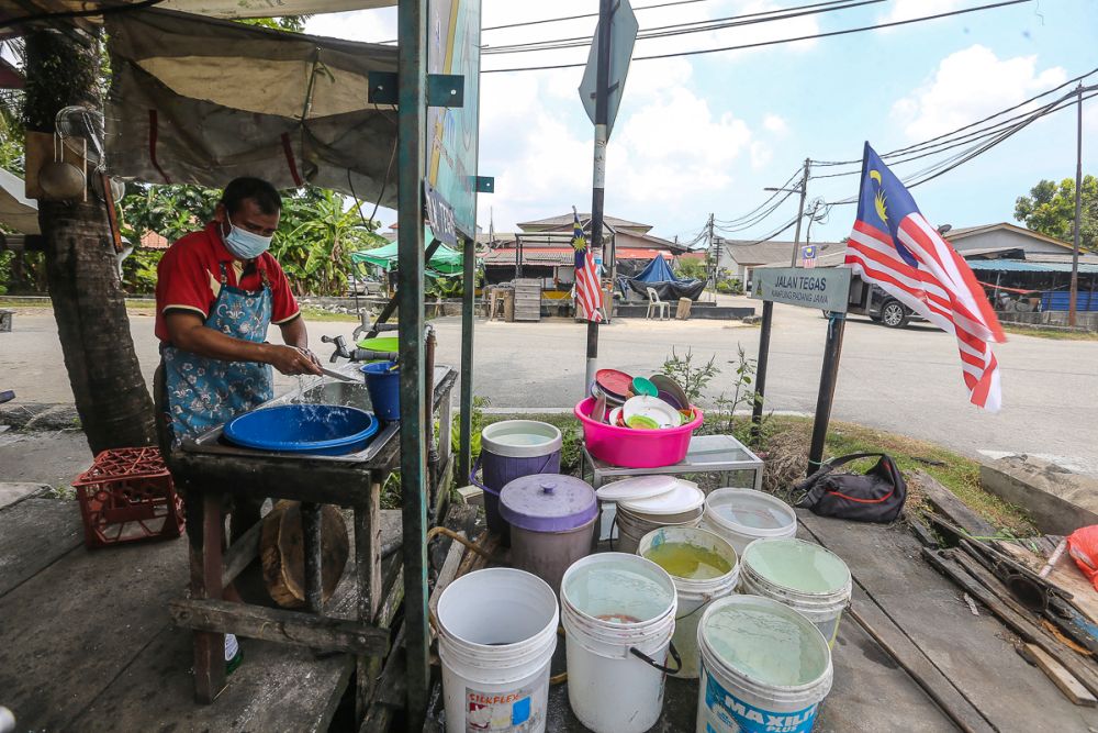 A worker is seen washing dishes at a  food stall using water stored in containers in Kampung Jawa, Klang October 13, 2021. u00e2u20acu201d Picture by Yusof Mat Isa