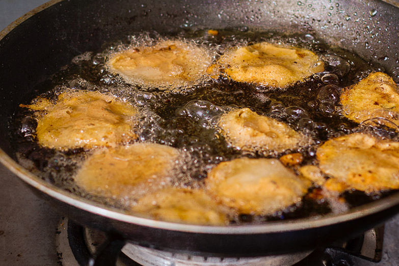 Pakoras frying in hot oil.